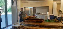 Wnętrze muzeum z obiektami na stołach i prezentujący je pracownik